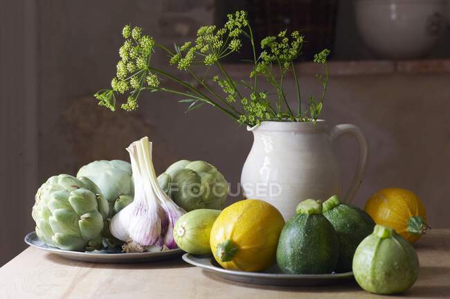 A still life with round courgettes, garlic and artichokes — Stock Photo
