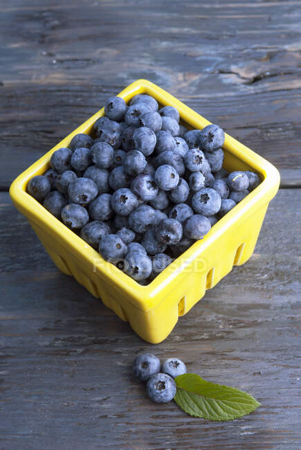 Fresh blueberries in the wicker basket on wooden table, selective focus — Stock Photo