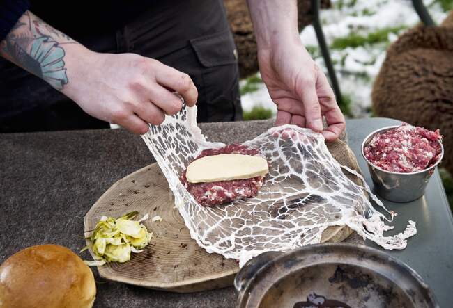 Preparación de hamburguesas para acampar: Envuelva las empanadas de carne en un caul de cerdo - foto de stock