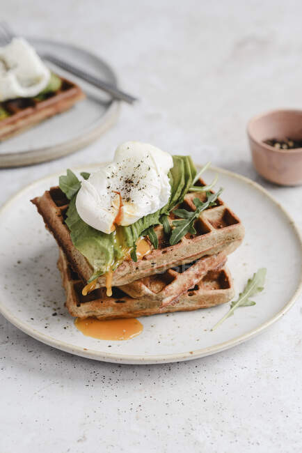 Waffles with avocado, arugula and poached egg — Stock Photo