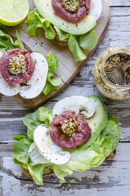 Sanduíches abertos com tártaro de vaca, mostarda, cogumelos, abacate e alface — Fotografia de Stock