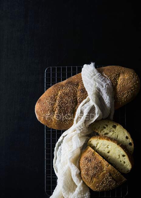 Italian semolina bread on a cooling rack against a black background — Stock Photo