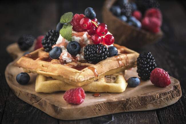 Waffles belgas com sorvete e bagas em uma tábua de madeira — Fotografia de Stock