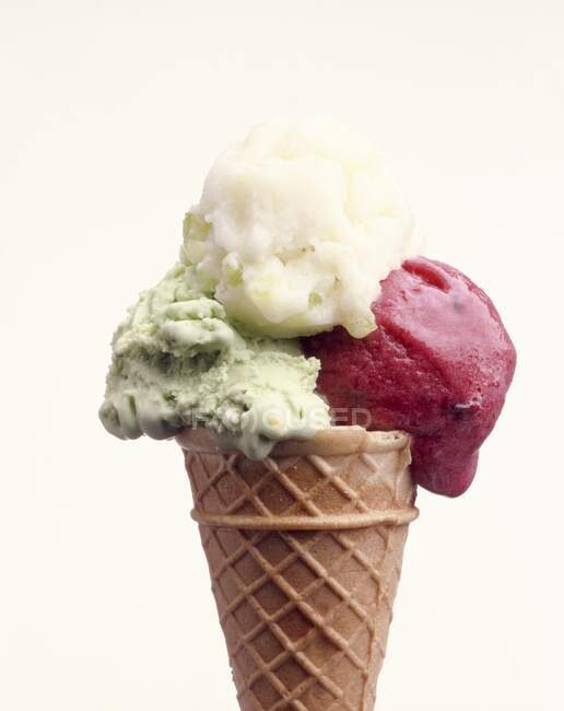 Un cône avec trois cuillères de crème glacée aromatisée différente — Photo de stock