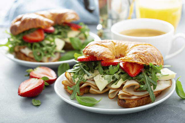 Sanduíche de pequeno-almoço em um croissant com peru, rúcula, morangos e brie — Fotografia de Stock