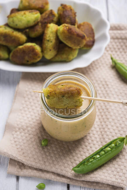 Vegan peas and potatoes croquettes from pan with herbs sauce in jar — Stock Photo