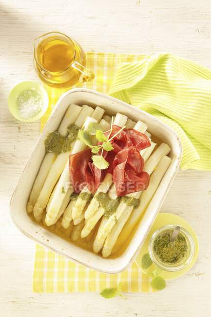 Oven-baked asparagus with pesto, lemon balm and bresaola — Stock Photo