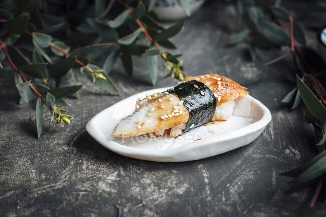 Nigiri sushi con semillas de anguila y sésamo en mini plato - foto de stock