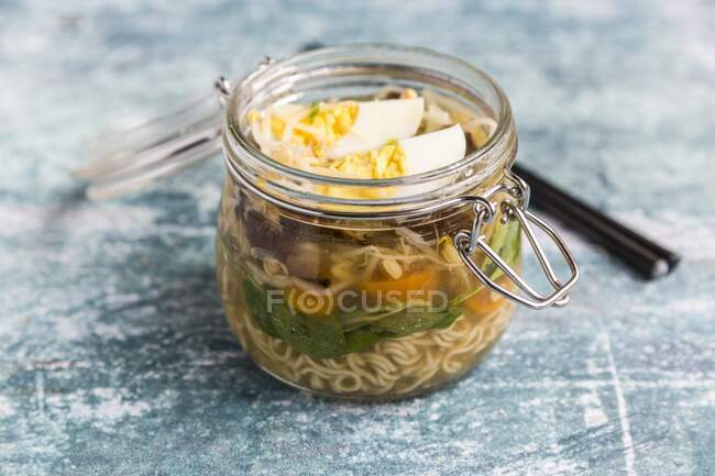 Sopa de ramen com espinafre, brotos de bambu, cenouras, ovo e cogumelos em um frasco de vidro — Fotografia de Stock