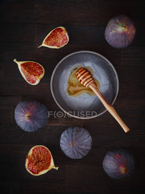 Figos frescos e um mergulhador de mel em um fundo de madeira escura — Fotografia de Stock