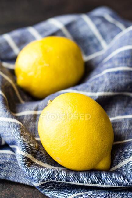 Zwei Zitronen auf einem blau-weiß gestreiften Leinentuch — Stockfoto