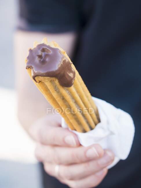 A person holding a churro in their hand — Stock Photo