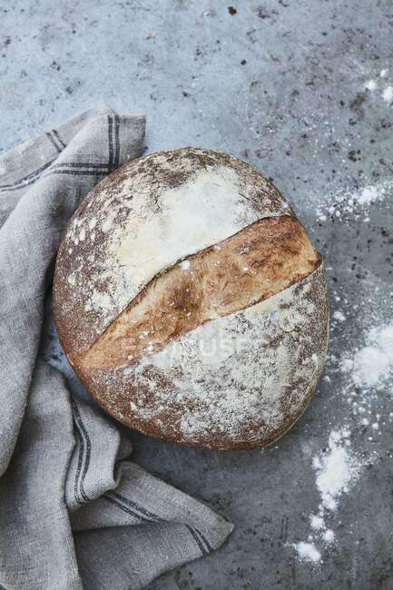 Um pão com um pano de linho em um chão de pedra (vista superior) — Fotografia de Stock