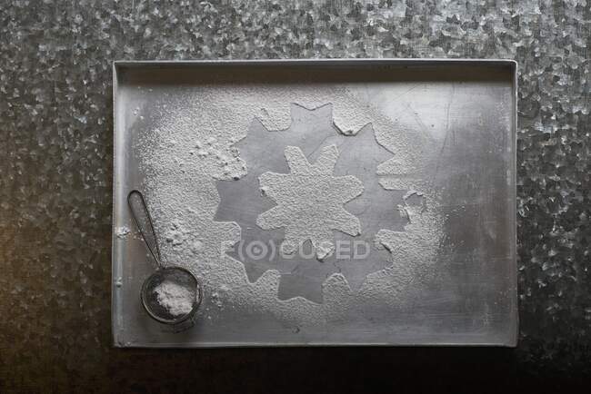 An icing sugar snowflake on a baking tray (seen from above) — Stock Photo