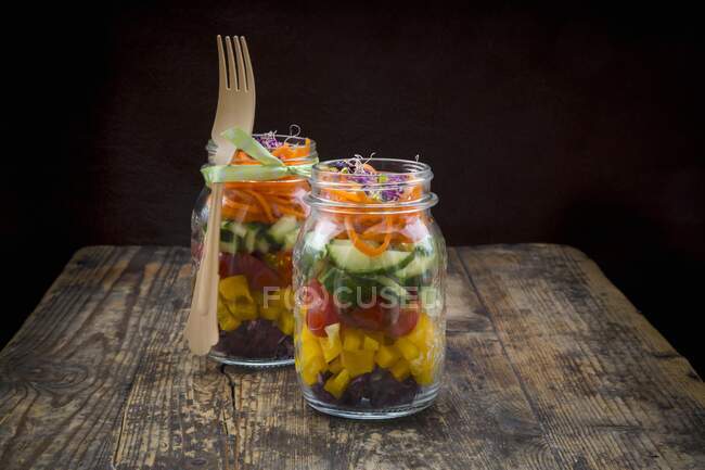 Rainbow salad in glass jars with red cabbage, yellow pepper, tomato, cucumber, carrots and beetroot sprouts — Stock Photo