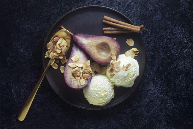 Red wine pears with vanilla ice cream and roasted almonds — Stock Photo