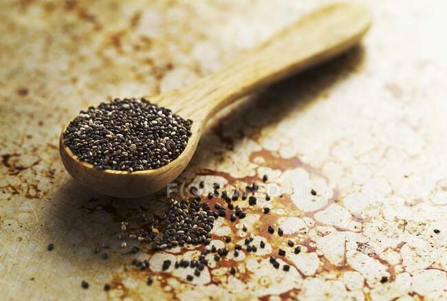 Chia seeds in a wooden spoon on an old baking sheet — Stock Photo