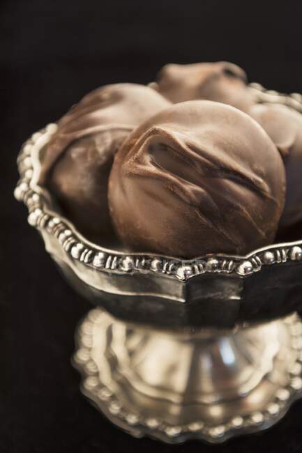 Chocolate confectionery with macadamia nuts in a silver bowl (close up) — Stock Photo