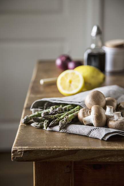 Espárragos verdes y champiñones marrones en toalla de cocina - foto de stock