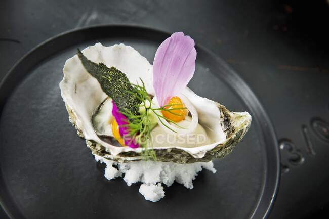 An oyster being decorated with flower petals — Stock Photo