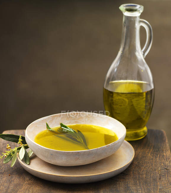 Olive oil in a bowl with herbs and spices on a dark background. — Stock Photo