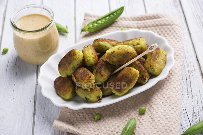 Potatoes croquettes with herbs sauce in glass jar — Stock Photo