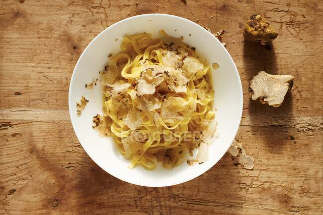 Tagliatelle with truffle mushrooms flakes on wooden table — Stock Photo