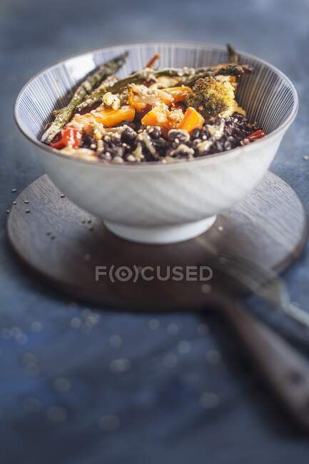 Tazón vegano con arroz negro, verduras tostadas y salsa tahini - foto de stock