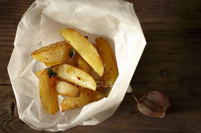 Hausgemachte Kartoffelkeile in Papier mit Knoblauch — Stockfoto