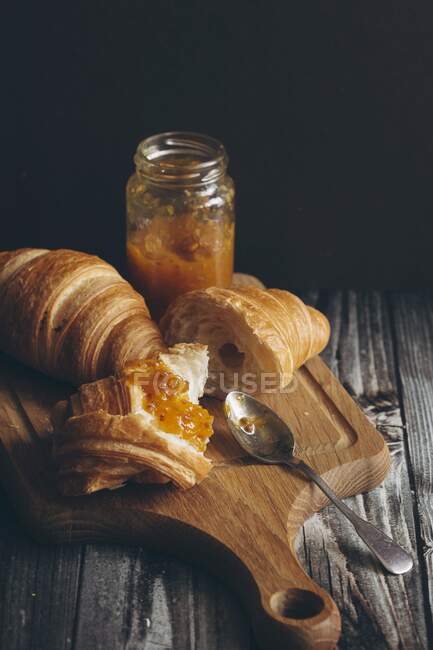 Croissants and marmalade on a chopping board — Stock Photo