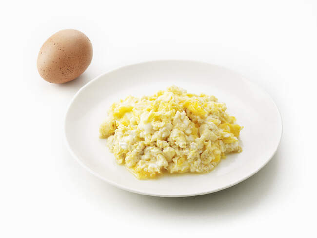 Scrambled eggs and boiled egg in a white dish on a light background — Stock Photo