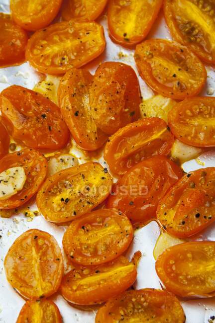 Roasted orange grape tomatoes and garlic on a roasting pan — Stock Photo