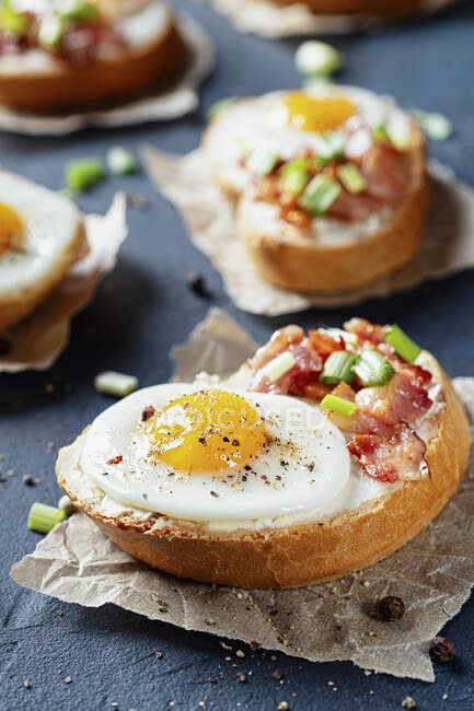 Crostini with bacon, spring onions and quail's eggs — Stock Photo