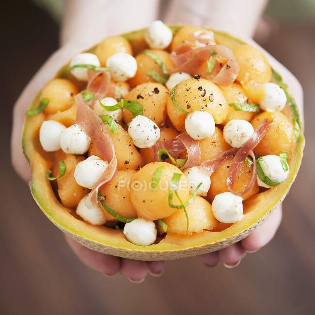 Melon salad with mozzarella and proscuitto in a hollowed-out melon — Stock Photo
