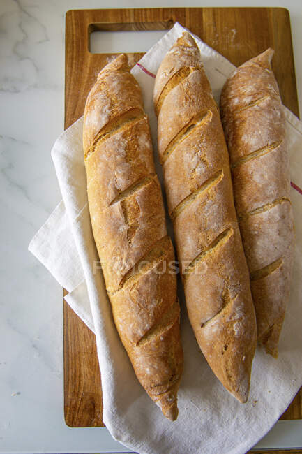 Three baguettes on a wooden chopping board — Stock Photo