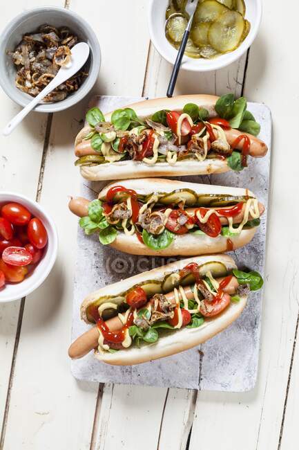 Гарячі собаки з салатом, помідорами, грибами, кетчупом, гірчицею та підсмаженою цибулею — стокове фото