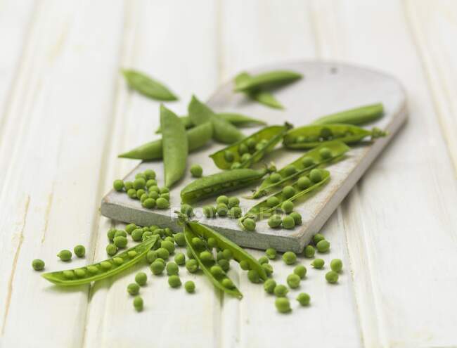 Peas and pea pods on a chopping board — Stock Photo