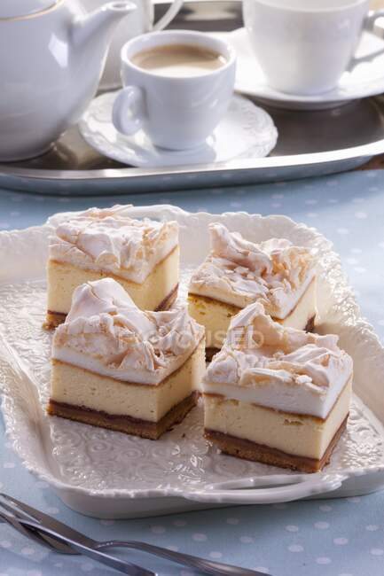 Quatre morceaux de gâteau au fromage garnis de meringue, servi avec du café — Photo de stock