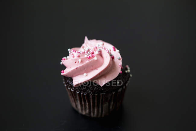 A chocolate cupcake with raspberry cream and sugar sprinkles — Stock Photo
