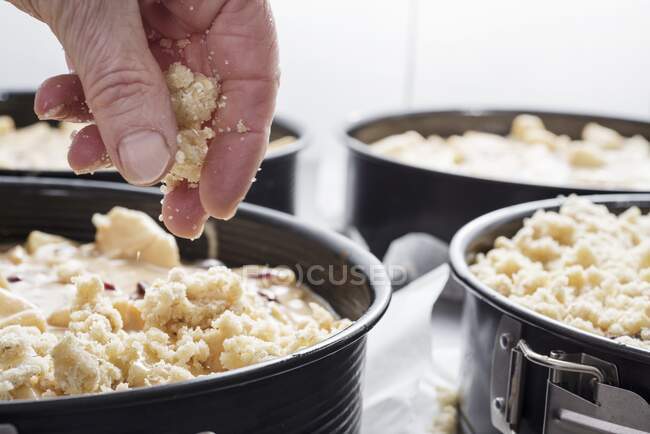 Crumble topping being added to an apple and berry cake — Stock Photo