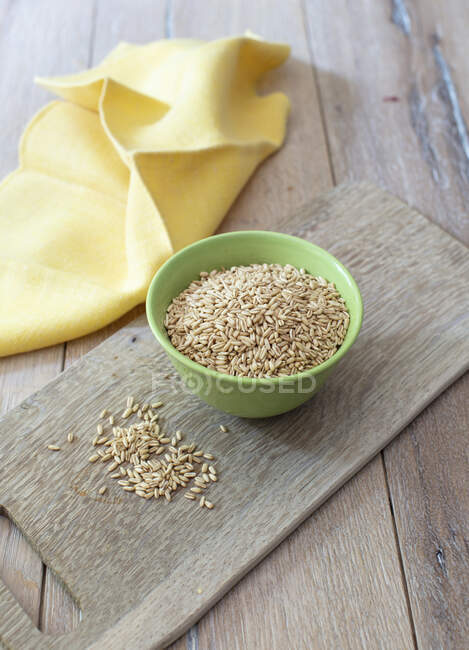 Raw organic rice in a bowl on a wooden background — Stock Photo