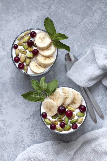 Yoghurt muesli with cranberries, pistachios and banana slices — Stock Photo