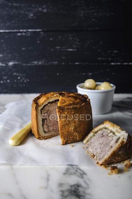 Pork pie cut on paper at marble board surface — Stock Photo