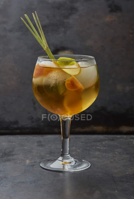 Cocktail with fruit slices and lemongrass in glass — Stock Photo