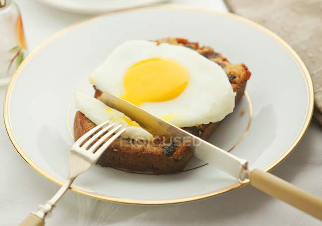 Poached egg on banana bread cut with knife and fiork — Stock Photo