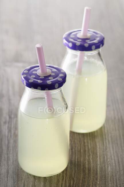Limonada en dos botellas con paja - foto de stock