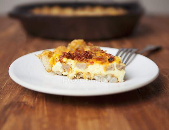 A slice of tater tot bake topped with bacon and egg (USA) — Stock Photo
