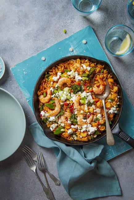 Orzo pasta cooked in tomato sauce with king prawns, vegetables and crumbled feta cheese — Stock Photo