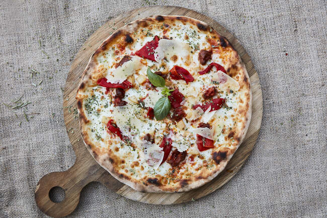 A cheese pizza with bresaola and basil — Stock Photo