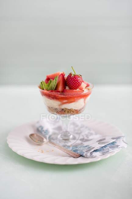 Strawberry and vanilla cheesecake with nut and biscuit base in a glass — Stock Photo